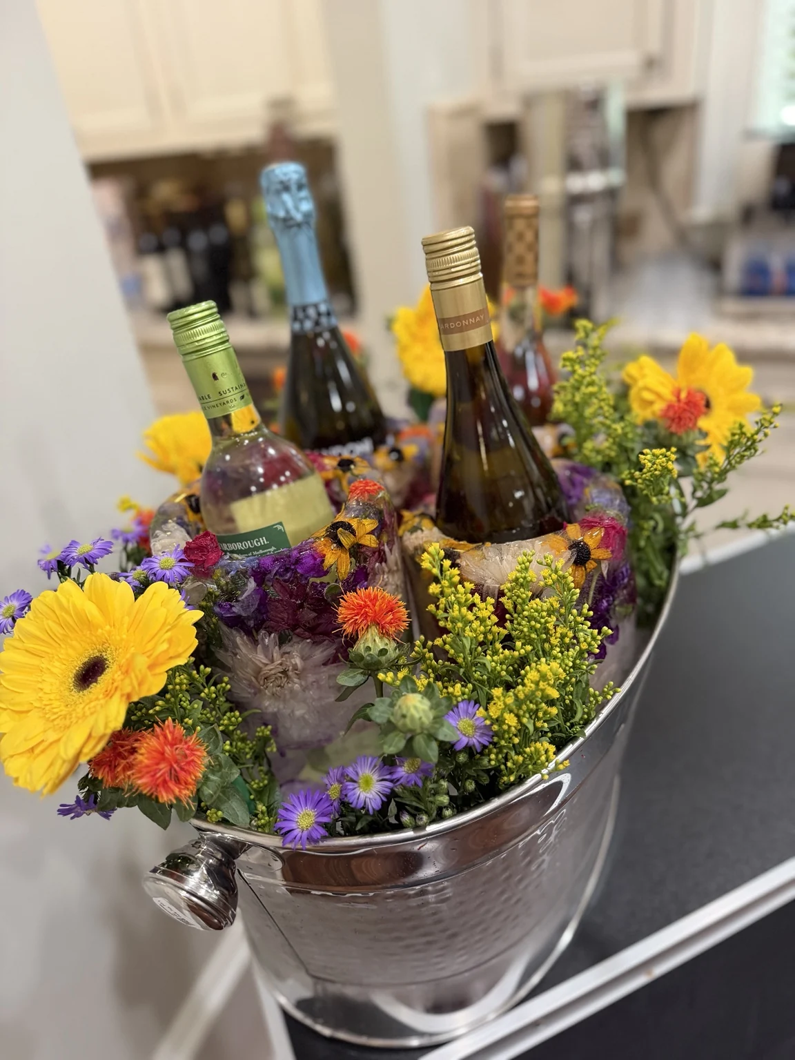 Wine bottles chilled in floral ice with yellow, orange and purple coordinating flowers