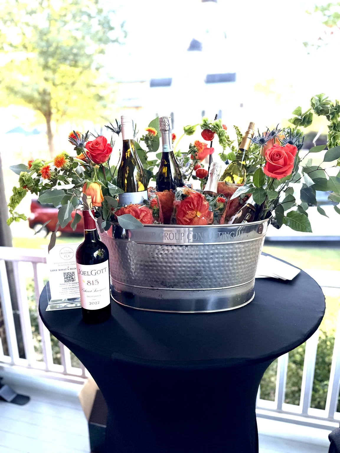 Wine bottles in floral ice chillers with orange roses at a corporate anniversary party