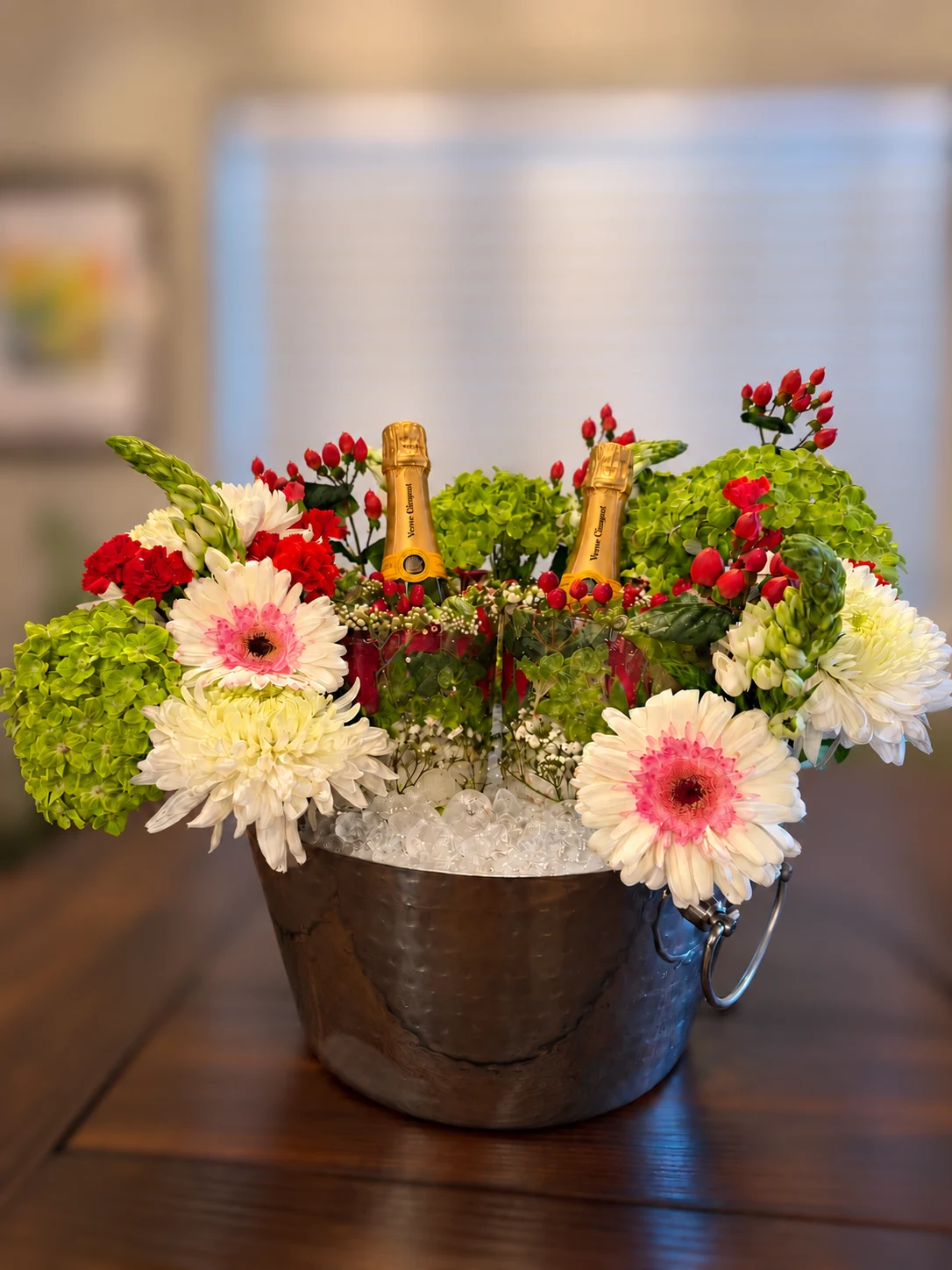 Pink and white flowers surrounding two floral ice bottle chillers in a silver bucket
